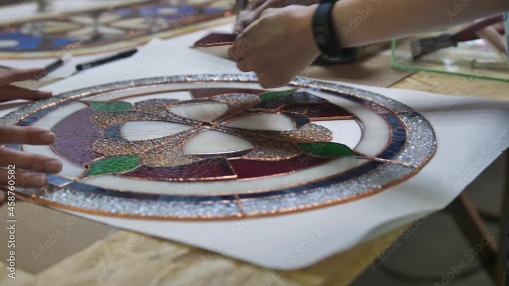 Two artists assemble a composition from stained glass windows