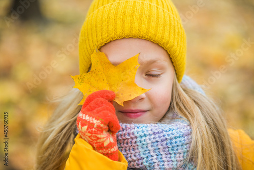 Little blond girl in yellow clothing with yellow leaf  autumn
