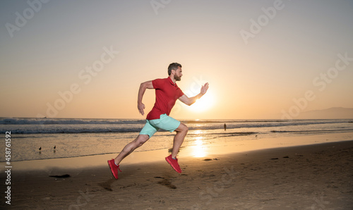 sportsman sprinter running on sunrise summer beach at ocean, jogging