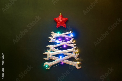Creative christmas tree on black background, made of wrenches. Industrial greeting card and happy new year concept.