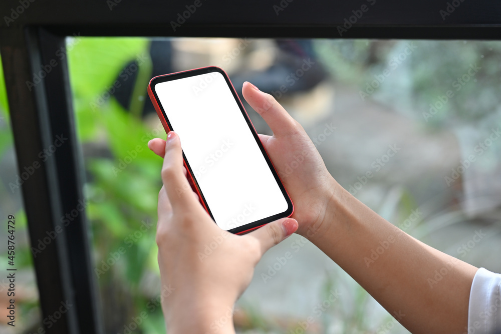 Closed up of a woman's hand using a white screen smartphone over a comfortable living room as a background.