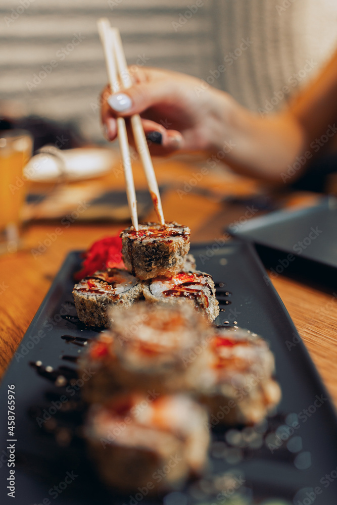 Fototapeta premium Close up of a sushi plate with a female hand holding chopsticks
