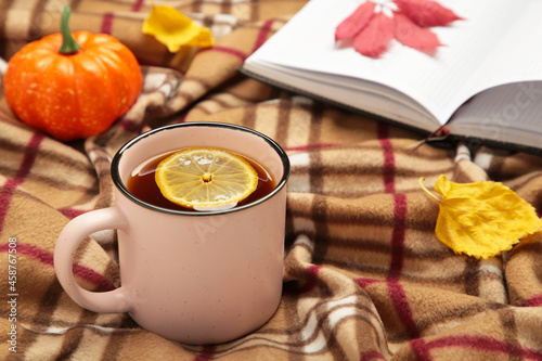 Hot tea and autumn leaves with notebook on plaid - seasonal relax concept. Cozy concept