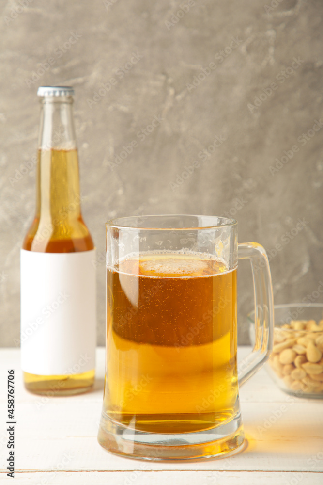Glass of beer with peanuts on grey background. Vertical photo Glass of beer with peanuts on grey background. Vertical photo