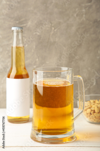 Glass of beer with peanuts on grey background. Vertical photo