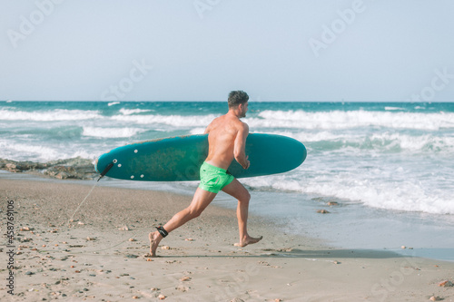 Man surfer run in ocean with surfboard. Active vacation, health lifestyle and sport concept image