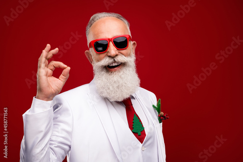 Photo of happy charming positive man make okay sign recommend wear sunglass isolated on red color background