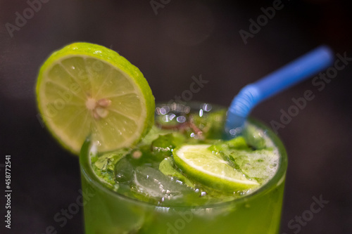 Green cocktail with lime and ice and blue straw