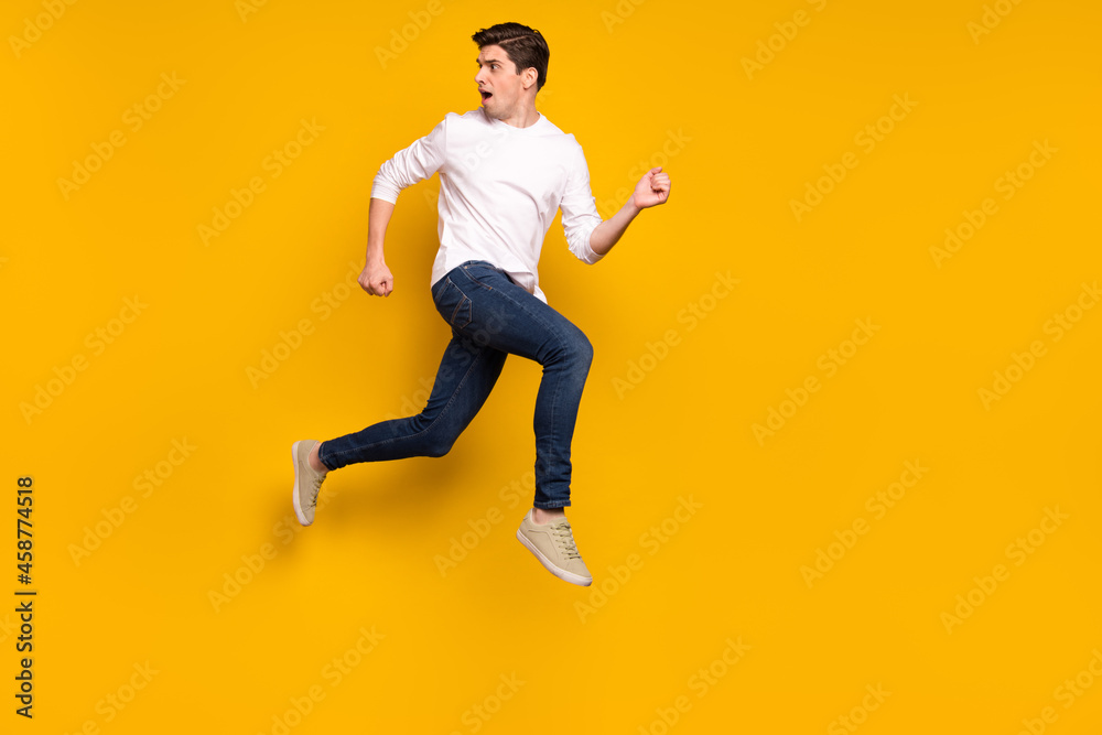 Full size profile photo of afraid brunet millennial guy run wear shirt jeans sneakers isolated on yellow background