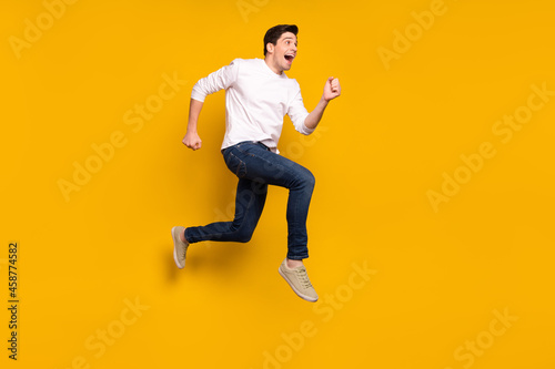 Full body profile photo of funny brunet young guy run wear shirt jeans sneakers isolated on yellow background