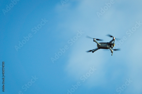 Flying copter against the blue sky. Copter in motion. Small flying drone.