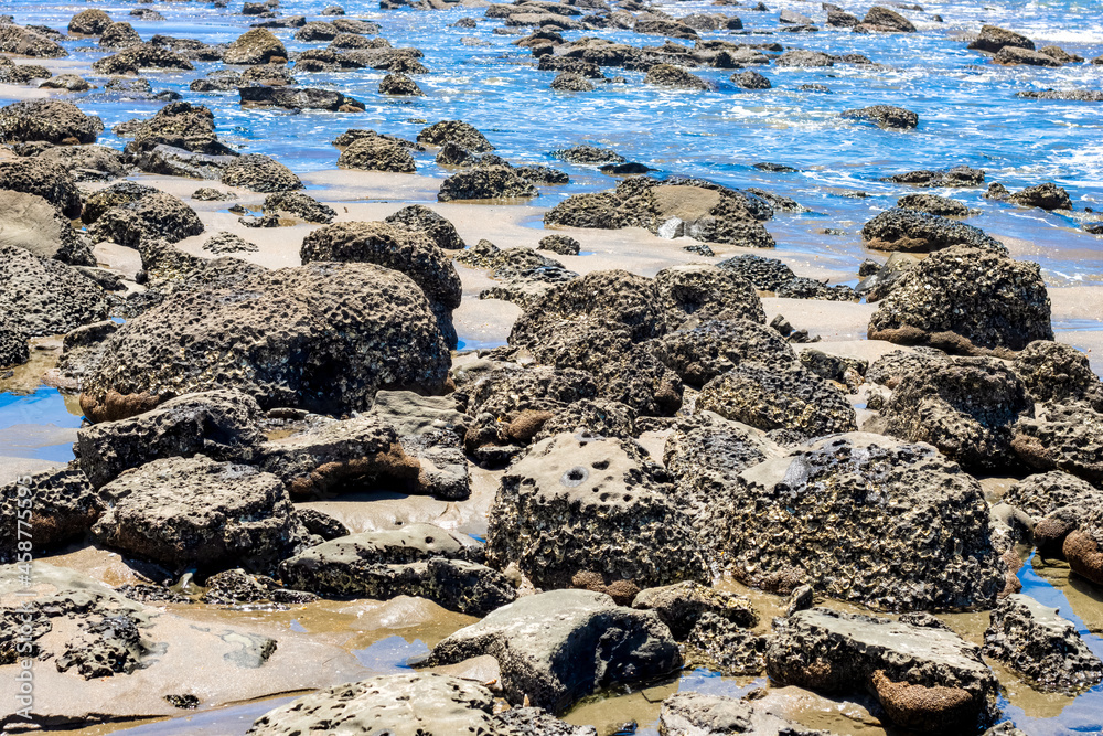 Scattered stones on a sea beach with blue water close up view