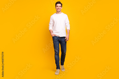 Full length body size photo brunet guy in casual outfit smiling confident walking forward isolated vibrant yellow color background