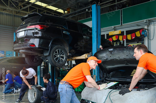 Mechanic workers working with engine at garage, car service technician checking and repairing the customer car at automobile service center, vehicle repair service shop concept