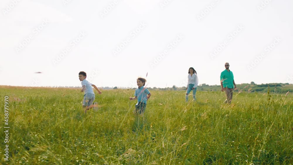 Beautiful young family two cute kids and parents at the picnic in the middle of large field chilling and walking together with their dog english cocker spaniel Beautiful young family two cute kids and parents at the picnic in the middle of large field chilling and walking together with their dog english cocker spaniel