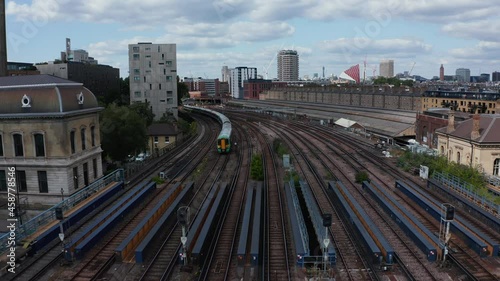 Backwards tracking of passenger train driving on wide multitrack railway bridge over river. London, UK photo