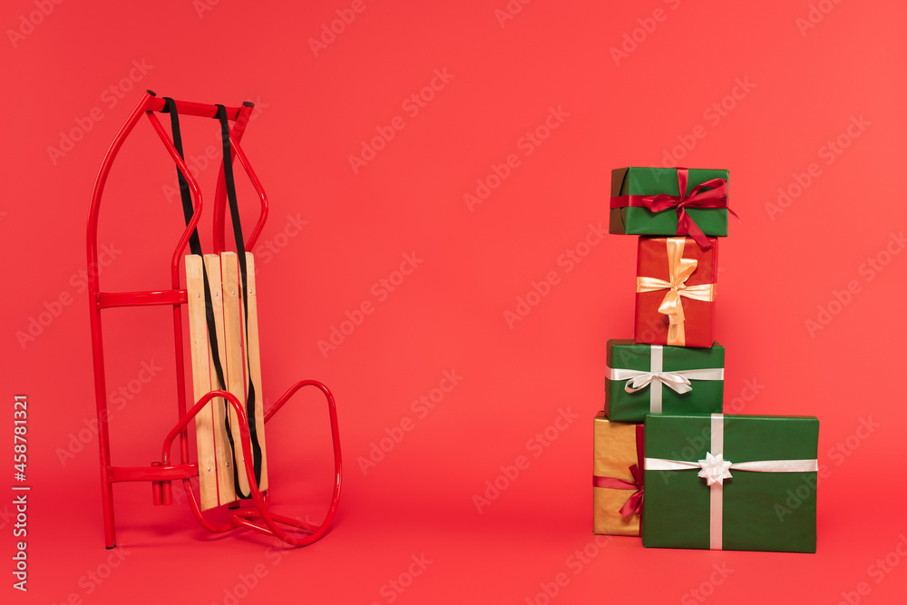 stack of multicolored gift boxes near sled on red stack of multicolored gift boxes near sled on red