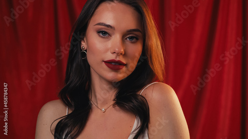 gorgeous and flirty woman looking at camera on red.