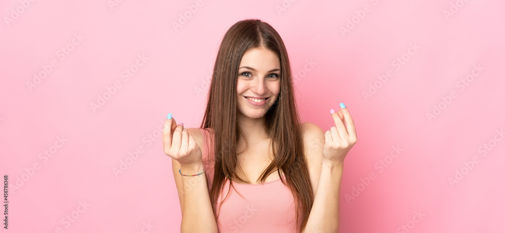 Young caucasian woman isolated on pink background making money gesture