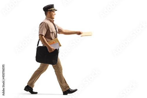 Full length profile shot of a mailman walking and delivering a letter
