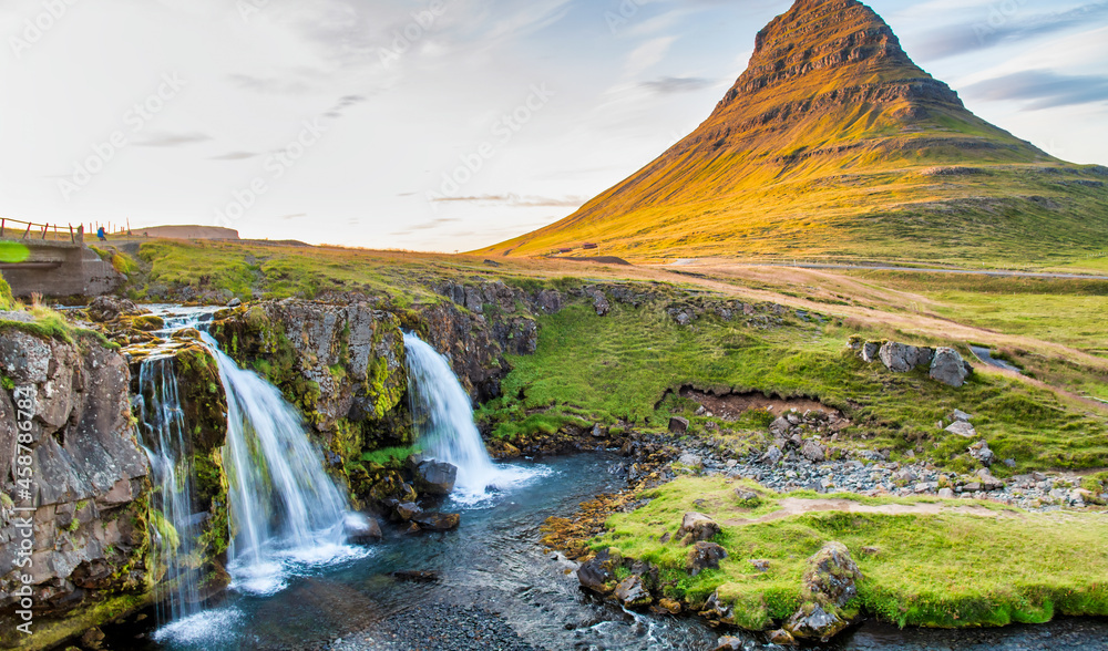 Kirkjufell Waterfalls and Mountain at sunset, wide angle view on a sunny summer day