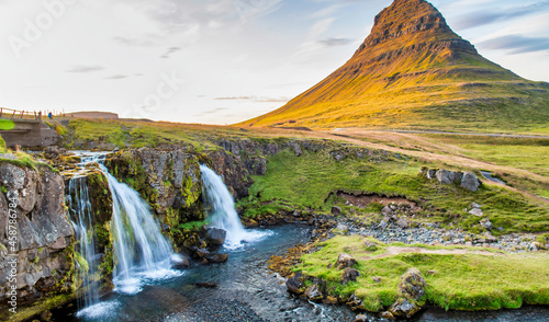 Kirkjufell Waterfalls and Mountain at sunset  wide angle view on a sunny summer day