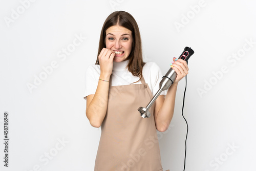 Young woman using hand blender isolated on white background nervous and scared