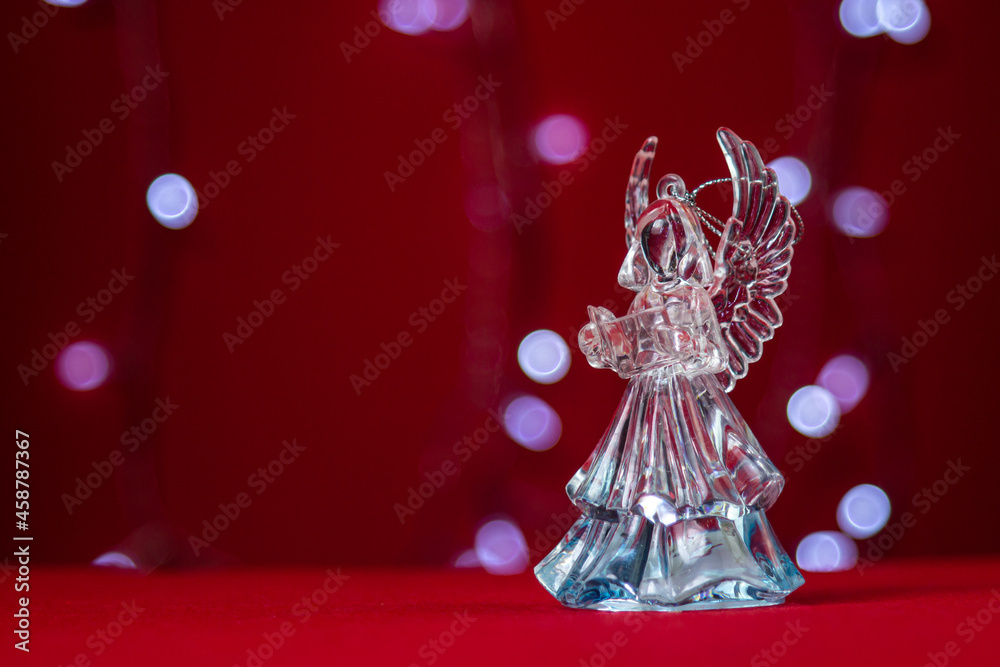 Glass figurine of an angel on a festive background. The concept of Christmas and religious holiday