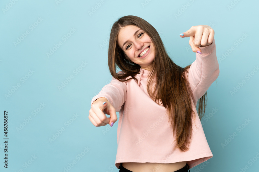 Fototapeta premium Young caucasian woman isolated on blue background pointing front with happy expression