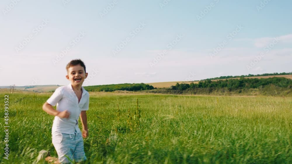 Excited small boy with his cute dog English cocker spaniel enjoy the time at nature running through the grass in a perfect sunny day