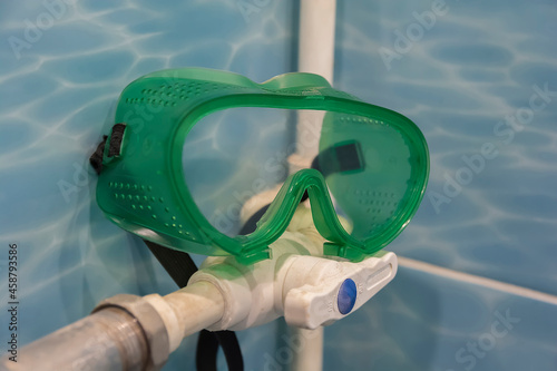 green safety glasses with large glass lie on a white plastic pipe