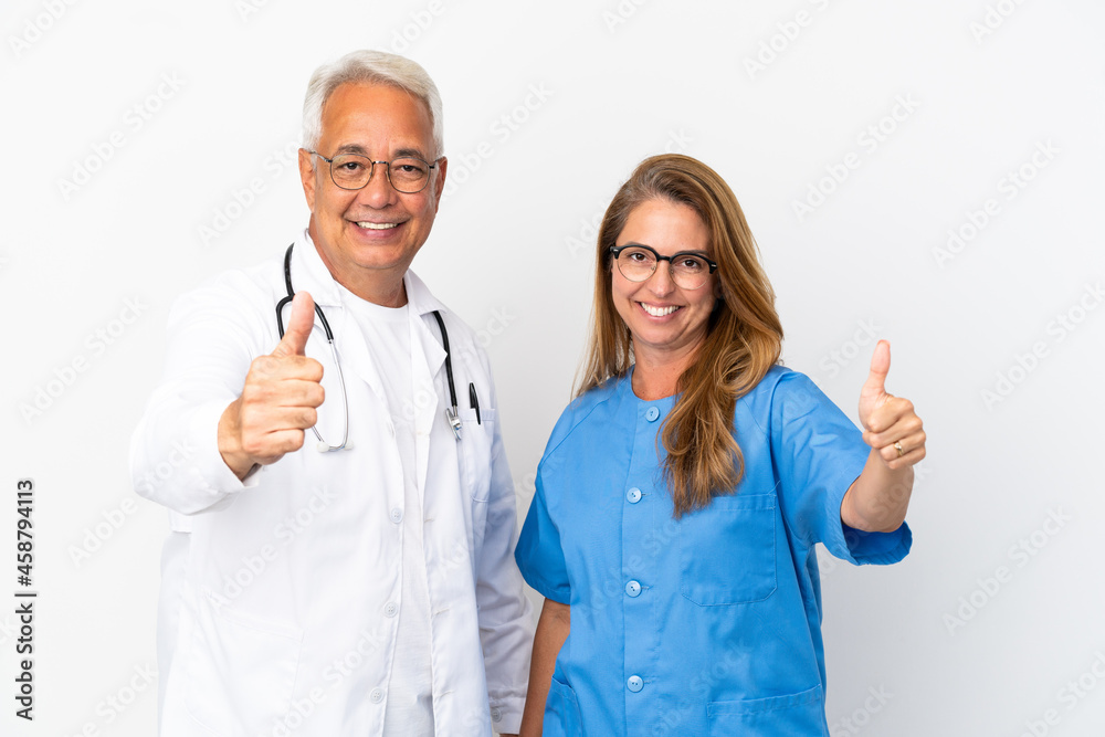 Middle age doctor and nurse isolated on white background giving a thumbs up gesture because something good has happened Middle age doctor and nurse isolated on white background giving a thumbs up gesture because something good has happened