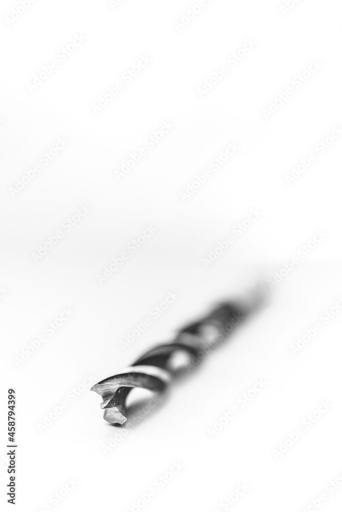 A black and white studio portrait of a spiral high speed steel wood drill bit on a white background. The metal tool is used to drill holes into wood for build or construction or repair work. A black and white studio portrait of a spiral high speed steel wood drill bit on a white background. The metal tool is used to drill holes into wood for build or construction or repair work.