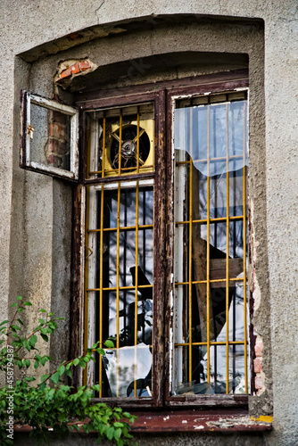 Stary budynek ( kamienica ) okno , kraty , klimatyzator, wybite szyby. Old building (tenement house) window, grilles, air conditioner, knocked glass. 