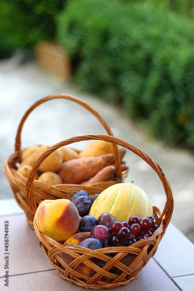 Two baskets full of fresh fruit and vegetable in a garden. Selective focus.