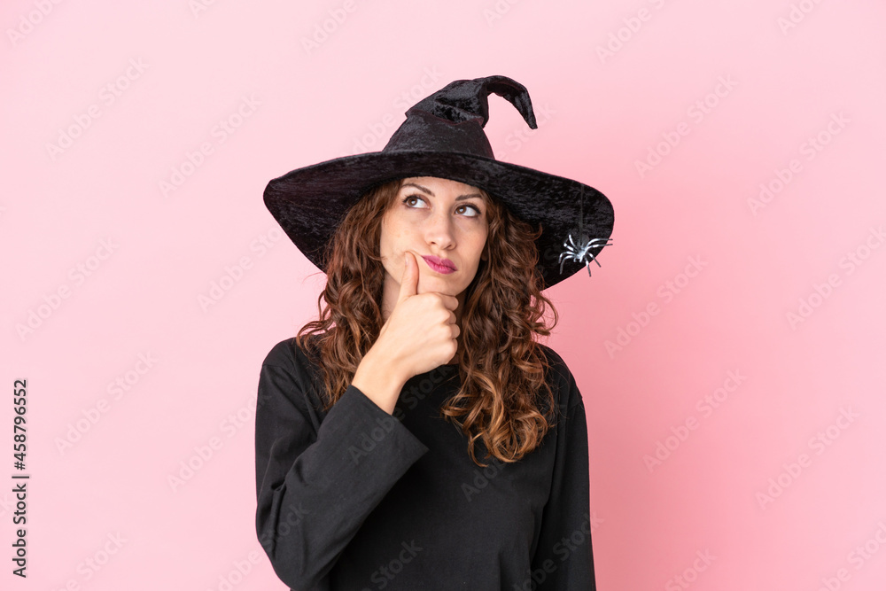 Young caucasian woman celebrating halloween isolated on pink background having doubts and with confuse face expression