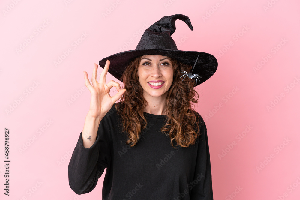 Young caucasian woman celebrating halloween isolated on pink background showing ok sign with fingers