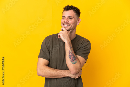 Young caucasian handsome man isolated on yellow background looking to the side and smiling
