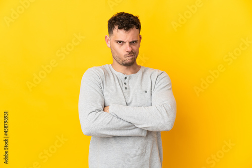 Young caucasian handsome man isolated on yellow background with unhappy expression
