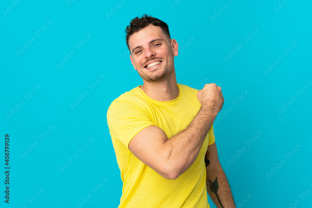 Young caucasian handsome man isolated on blue background celebrating a victory Young caucasian handsome man isolated on blue background celebrating a victory