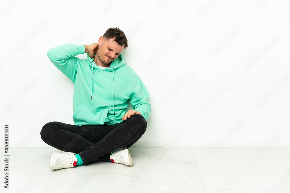 Young handsome caucasian man sitting on the floor with neckache Young handsome caucasian man sitting on the floor with neckache