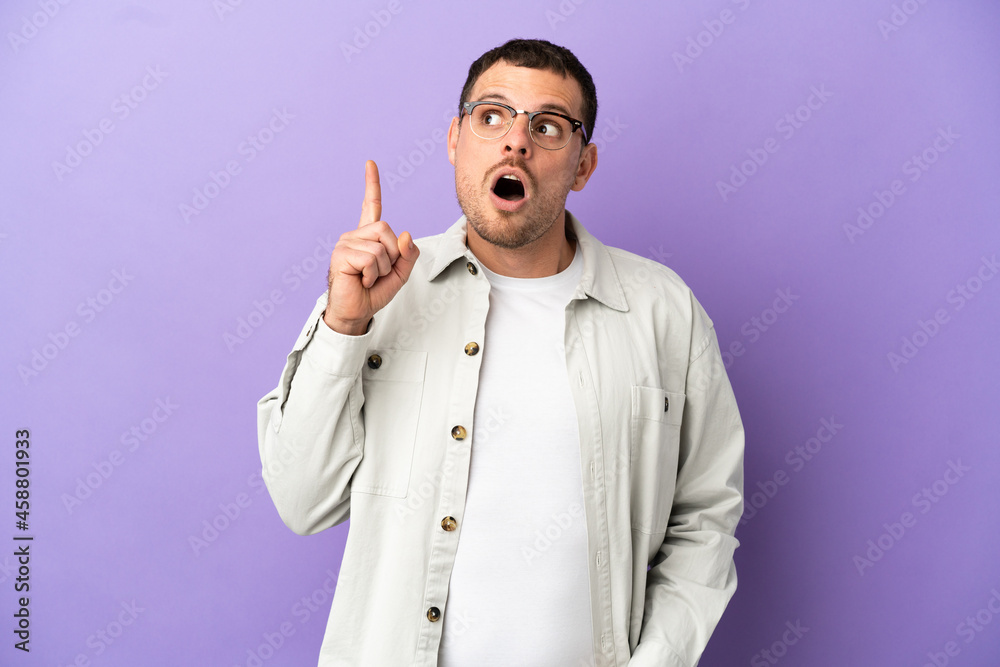 Brazilian man over isolated purple background thinking an idea pointing the finger up Brazilian man over isolated purple background thinking an idea pointing the finger up