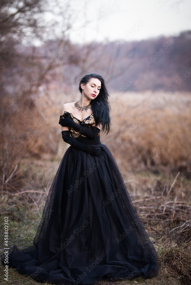 brunette in black dress in the woods