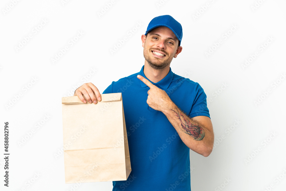 Brazilian taking a bag of takeaway food isolated on white background pointing to the side to present a product Brazilian taking a bag of takeaway food isolated on white background pointing to the side to present a product