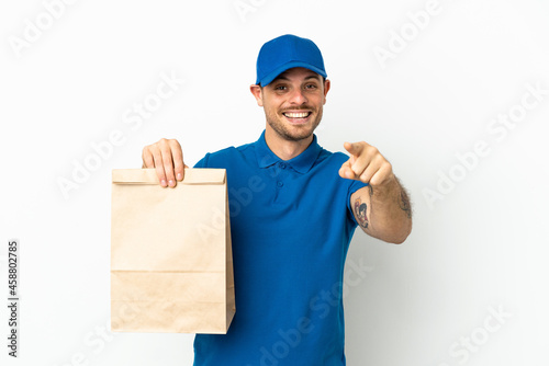 Brazilian taking a bag of takeaway food isolated on white background surprised and pointing front