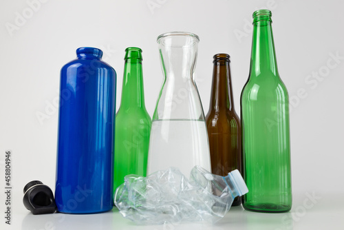 Aluminum water bottle, carafe and glass bottle, with a crumpled plastic bottle next to it. Plastic recycling and use of reusable materials. 