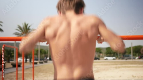 Young man doing muscle up on a bar practicing calisthenics exercices. photo