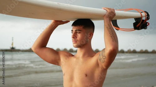 Surfer looking the sea while carrying a surfboard. photo