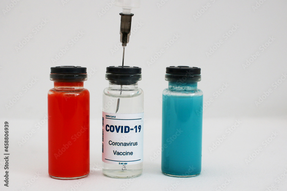 Three ampoules with covid-19 vaccine and a syringe on a white background. Three ampoules with covid-19 vaccine and a syringe on a white background.