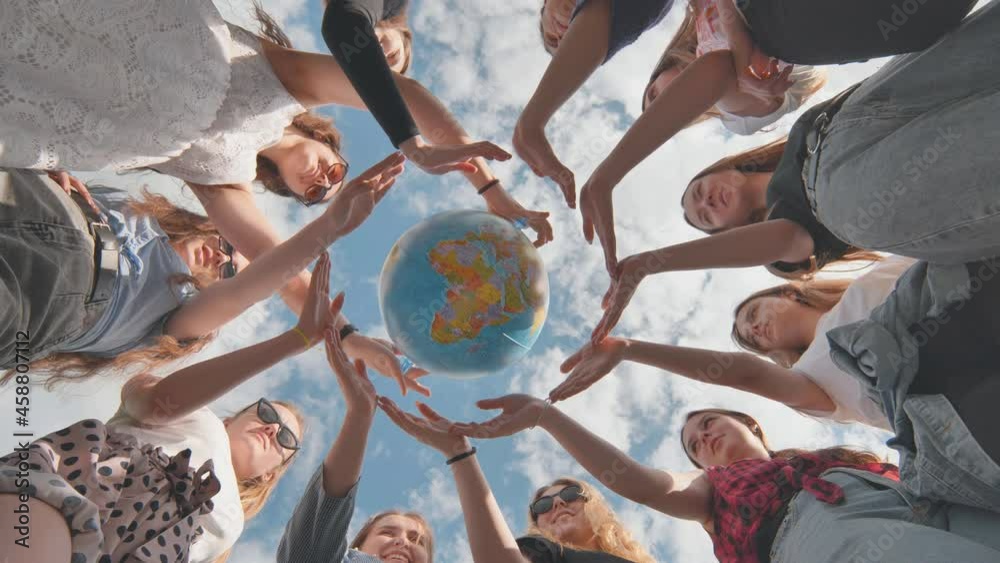 Earth conservation concept. 11 girls surround the rotating earth globe with their palms.